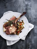 A veal chop with thyme on a lentil medley