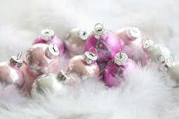 Pink Christmas tree baubles amongst feathers