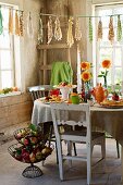 Gedeckter Tisch mit Apfelchips, Apfelgebäck, Blumenvasen und Teegeschirr