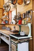 Simple kitchen in weekend house with small gas cooker and pans hung from rack