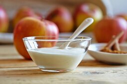 Natural yogurt in a glass bowl with fresh apples and cinnamon