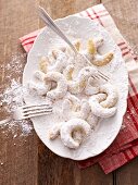 Vanilla crescent biscuits being rolled in icing sugar