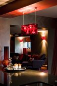 Dramatic lighting above kitchen counter; lounge area in background