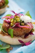 Chickpea burgers on unleavened bread with red onions, cucumber and a yoghurt suace