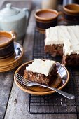 Carrot cake with an orange and cream cheese frosting with a slice on a plate