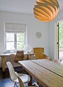 Eames Stühle an robustem Esstisch mit Designerleuchte, im Hintergrund ein Stuhl aus Palisanderstreben und ein Ledersessel