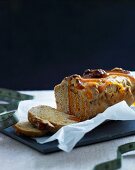 Sliced honey-nut loaf cake with orange syrup and baking paper on a chopping board