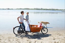 Paar mit Hund und Fahrrad auf dem Weg zum Strandpicknick