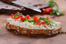 A slice of bread topped with cream cheese, tomatoes and rocket