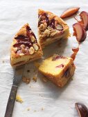 Three slices of gluten free plum cake with almonds and crumbles on parchment paper