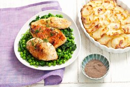 Chicken breast on a bed of peas and spinach served with potato gratin