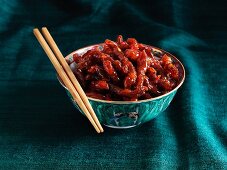 Crispy beef strips with chilli in an oriental bowls with chopsticks