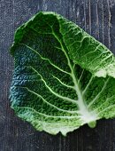 A savoy cabbage leaf on a weathered wooden surface