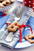 Alphabet biscuits and red ribbon tied around napkin on plate