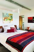 Ethnic blanket on double bed in modern bedroom