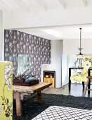 Floral patterns on wallpaper, lime-green fabrics and dark grey structured rug of home studio; chandelier above staircase in background