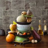 An arrangement featuring a stack of crockery, fruit, vegetables, mushrooms and ginger