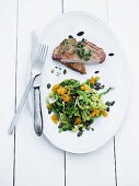 Pork chop with a green kale and orange salad