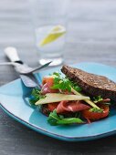 A rye bread sandwich with Parma ham, cheese, tomatoes and rocket