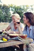 Two women eating Provençal food in a garden