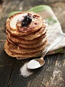 A stack of blueberry pancakes with sugar and blueberries