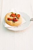 Focaccia with cherry tomatoes and basil on a wooden surface
