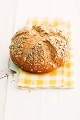 A loaf of sunflower seed bread on a checked napkin