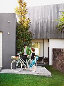 Mother on bike and son with skateboard in front of contemporary beach house in Queensland
