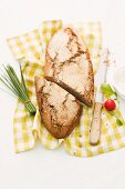 Rustic chestnut and bacon bread on a checked cloth with chives and radishes