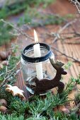 Christmas arrangement of candle in jam jar and reindeer-shaped biscuit