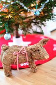 Tierfigur aus Stroh vor teilweise sichtbarem Weihnachtsbaum