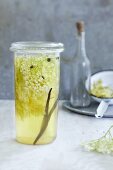 A jar of elderflower vinegar with a vanilla pod