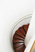 View down spiral staircase with wooden treads in circular stairwell