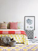 Scatter cushions in colourful mixture of graphic patterns on bed and rug with honeycomb pattern