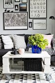 White and grey seating area with sofa, royal blue glass vase as focal point on DIY coffee table on castors and gallery of pictures in background