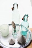 Swing-top bottles and ornaments on round metal tray