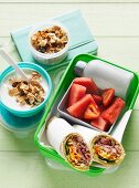 A lunchbox with wraps, fruit and muesli