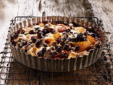 Apricot and blueberry clafoutis in a tart tin on a wire rack