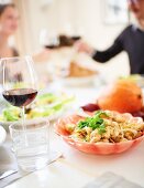 Paar prostet sich mit Rotweingläsern zu beim gedeckten Tisch zu Thanksgiving