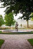 Stimmungsvoller Landschaftsblick mit künstlerischem Springbrunnen und gepflastertem Gartenplatz