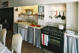 Simple kitchen counter with curtains on base units flanking gas cooker