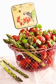 Erdbeeren und grüner Spargel im Drahtkorb mit nostalgischem Schild