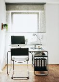 Cantilever chair with leather seat and classic desk in front of half-closed, translucent roller blind