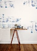 Improvised table on metal trestles against wall with blue plant-like structure on white background