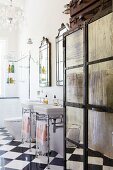 Vintage metal cupboard with mirrored panels next to twin washstands on metal frames on glossy chequered floor