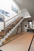 Blick auf Treppe mit Holztrittstufen in heller geräumiger Diele mit moderner Büste auf Staffelei