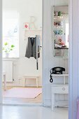 View into foyer with coat rack and vintage telephone