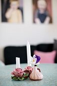 Crocuses in small vase next to candle holders shaped like roses