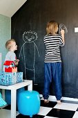 Kinder beim Malen an mit Tafellack gestrichener Wand