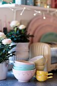 Bowls and cups next to potted roses on kitchen counter